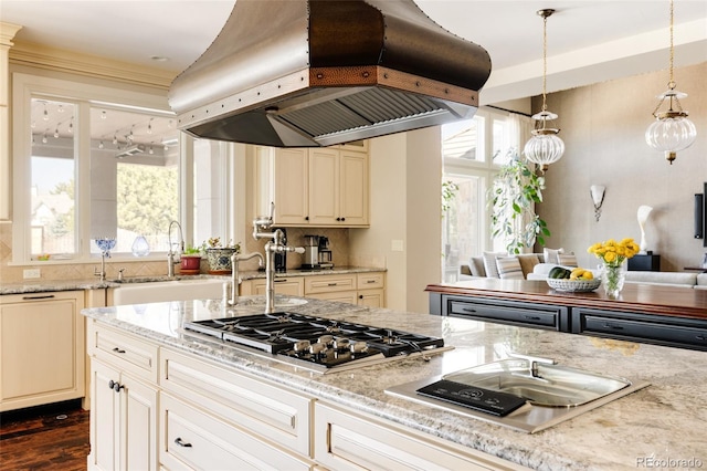 kitchen featuring stainless steel gas stovetop, a healthy amount of sunlight, a sink, premium range hood, and backsplash