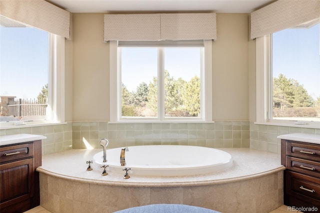 bathroom with a garden tub, vanity, and plenty of natural light