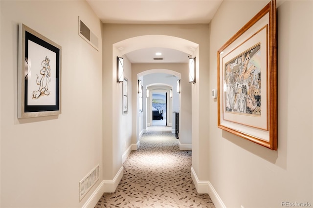 hallway with arched walkways, baseboards, and visible vents
