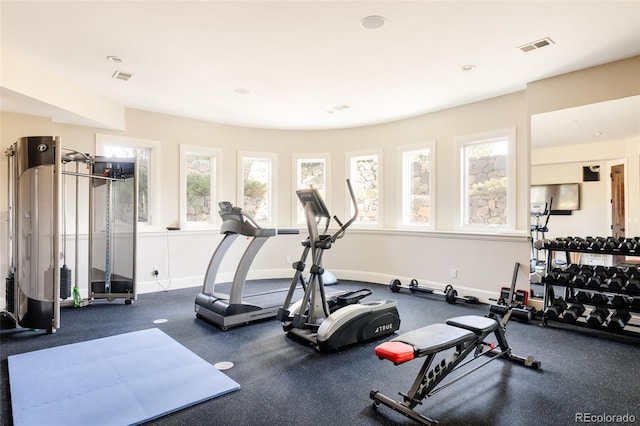 workout area with baseboards, a wealth of natural light, and visible vents