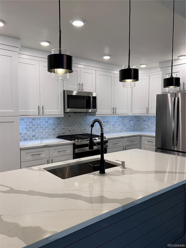 kitchen featuring light stone counters, hanging light fixtures, white cabinets, and stainless steel appliances