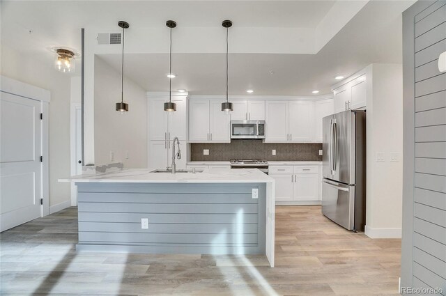 kitchen featuring white cabinets, decorative light fixtures, backsplash, and appliances with stainless steel finishes