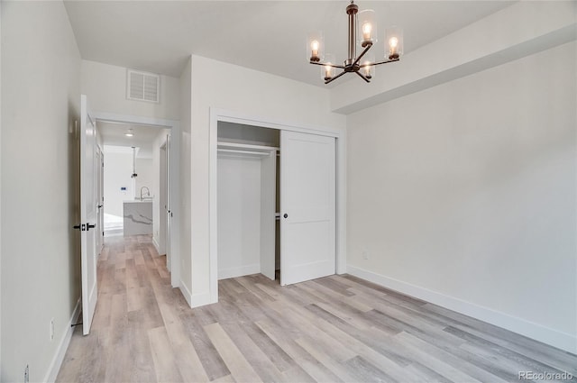 unfurnished bedroom with a chandelier, light hardwood / wood-style floors, and a closet