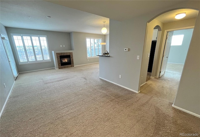 unfurnished living room with a tile fireplace and light carpet