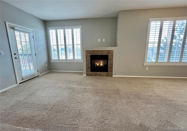 unfurnished living room featuring a tile fireplace and carpet flooring