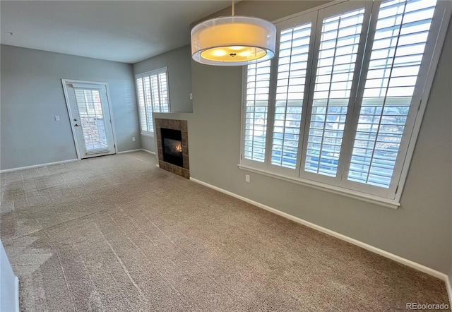 unfurnished living room with a tiled fireplace and carpet flooring