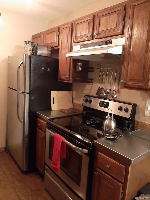 1525 Shadow Run Frontage Unit 204, Steamboat Springs, CO 80487 - kitchen featuring stainless steel range with electric cooktop, under cabinet range hood, brown cabinets, dark wood-style floors, and dark countertops
