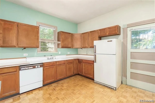 kitchen featuring light countertops, brown cabinets, white appliances, and a sink