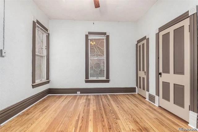 unfurnished room featuring baseboards, light wood-style flooring, and ceiling fan