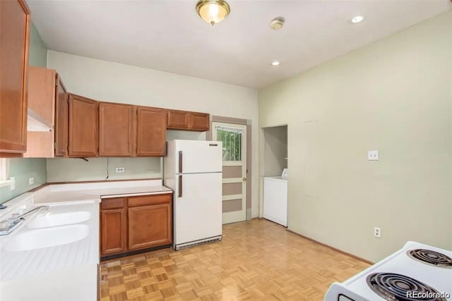 kitchen with light countertops, washer / dryer, brown cabinets, and white appliances