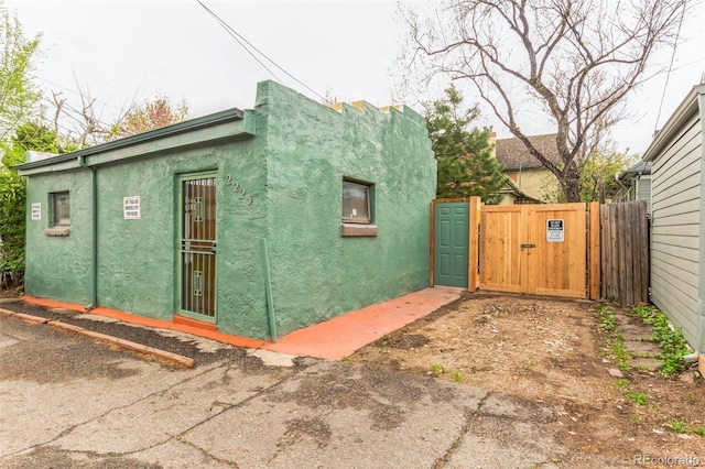 view of side of home featuring fence, a gate, and stucco siding