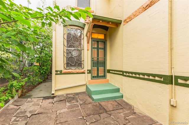 entrance to property featuring fence and stucco siding