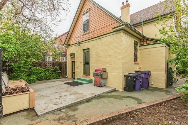 rear view of house featuring fence, a patio, a chimney, and entry steps