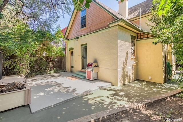 rear view of property featuring a patio area and a chimney