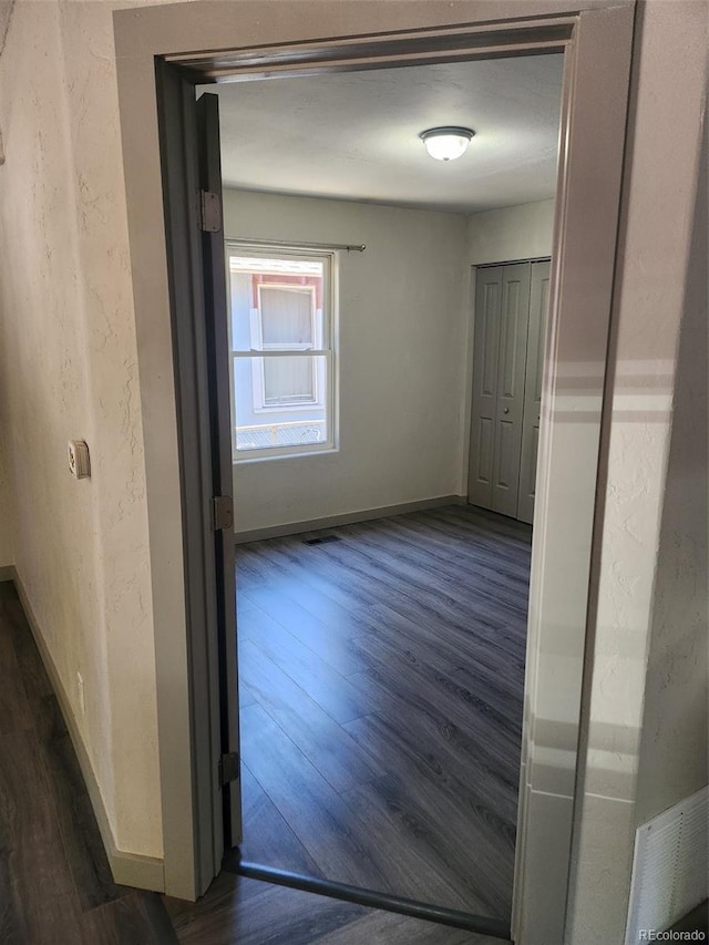 hall featuring visible vents, dark wood finished floors, and baseboards