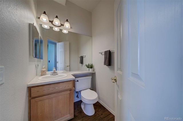 half bath featuring vanity, toilet, wood finished floors, and baseboards