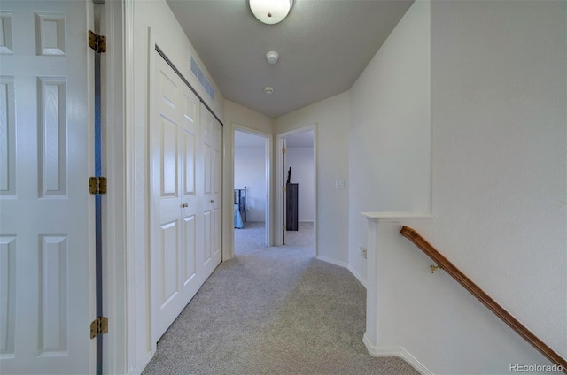 hall featuring visible vents, an upstairs landing, carpet, and baseboards