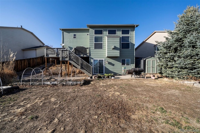 rear view of house featuring a shed, a wooden deck, stairs, an outbuilding, and a patio