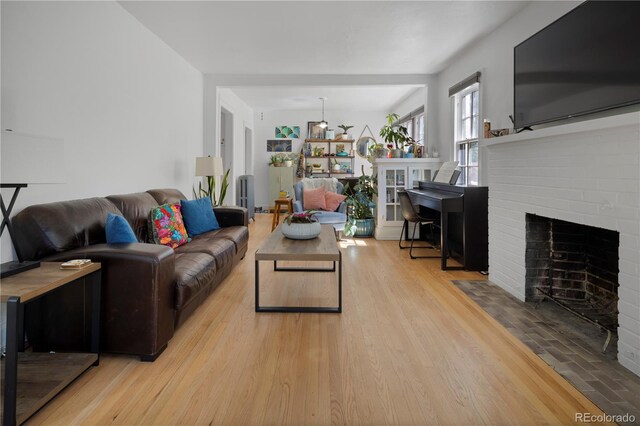 living room with a brick fireplace and light hardwood / wood-style flooring