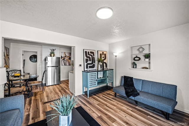 1209 E Routt Ave, Pueblo, CO 81004 - living area with wood finished floors, a textured ceiling, and built in shelves