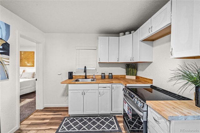 1209 E Routt Ave, Pueblo, CO 81004 - kitchen featuring electric range, butcher block counters, light wood-type flooring, and white cabinets