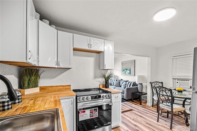 1209 E Routt Ave, Pueblo, CO 81004 - kitchen with electric stove, wood counters, white cabinetry, light wood-style floors, and cooling unit
