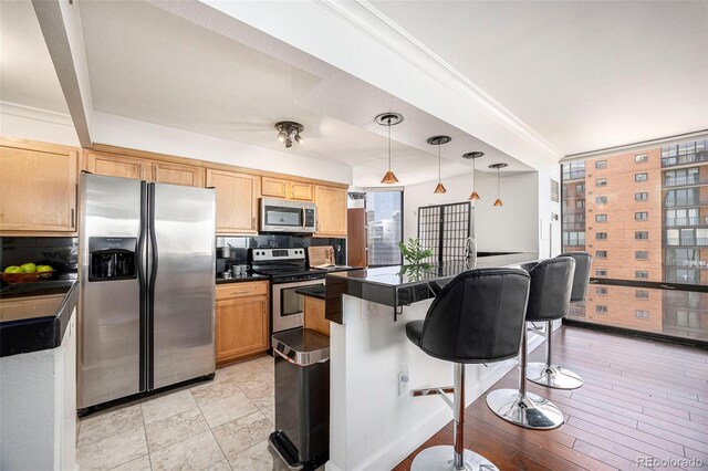 1625 Larimer St Unit 2601, Denver, CO 80202 - kitchen featuring stainless steel appliances, dark countertops, a breakfast bar area, decorative backsplash, and hanging light fixtures