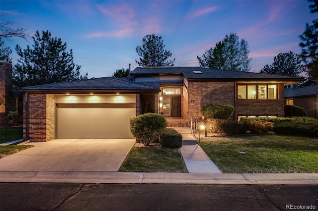 view of front of home with a garage, concrete driveway, a front yard, and brick siding