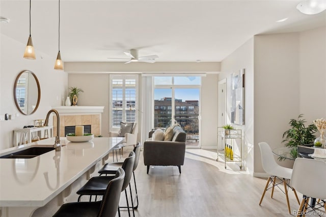 dining area with a kitchen bar, sink, decorative light fixtures, light hardwood / wood-style flooring, and a fireplace