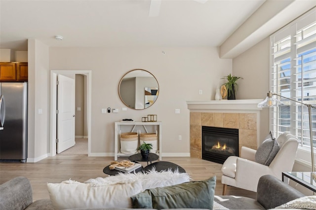 living room featuring a tiled fireplace, light wood-style flooring, and a wealth of natural light