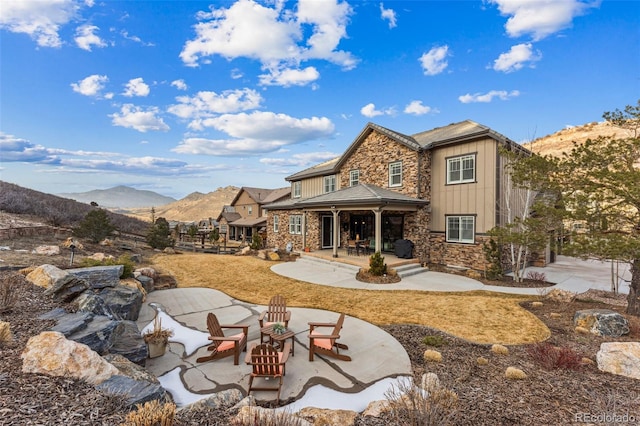 rear view of property with a fire pit, a mountain view, and a patio area