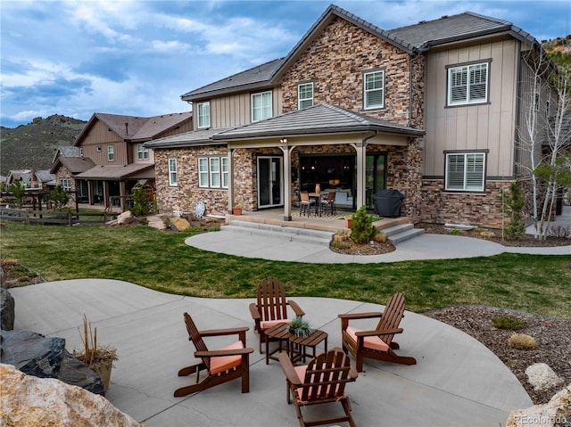 4937 Hogback Ridge Rd, Morrison, CO 80465 - rear view of house featuring a patio area, stone siding, board and batten siding, and a lawn