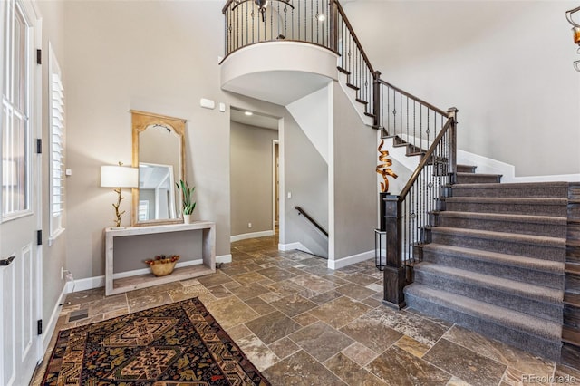 4937 Hogback Ridge Rd, Morrison, CO 80465 - entrance foyer featuring baseboards, stone tile flooring, a high ceiling, and stairway