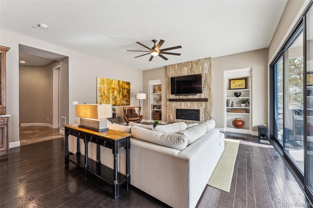 4937 Hogback Ridge Rd, Morrison, CO 80465 - living area featuring baseboards, built in features, a large fireplace, ceiling fan, and dark wood-type flooring