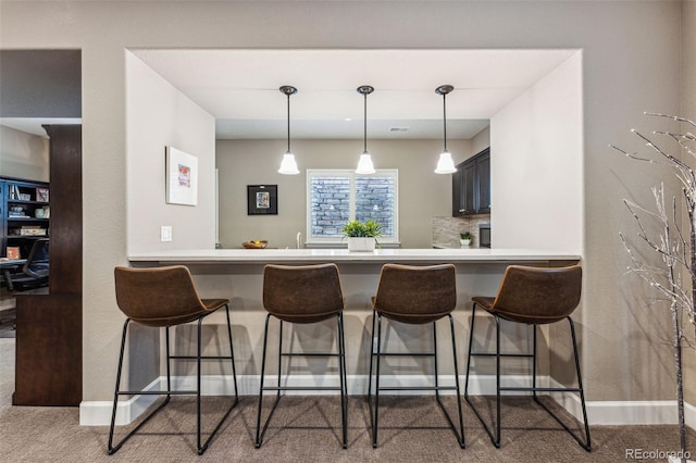 4937 Hogback Ridge Rd, Morrison, CO 80465 - kitchen featuring a peninsula, carpet floors, hanging light fixtures, and a breakfast bar area