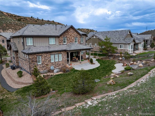 4937 Hogback Ridge Rd, Morrison, CO 80465 - rear view of house featuring a patio area, stone siding, and a lawn
