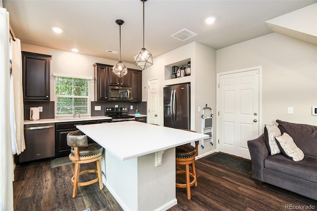 213 S Old Hammer Ct, Aurora, CO 80018 - kitchen with appliances with stainless steel finishes, a kitchen bar, dark wood finished floors, light countertops, and dark brown cabinets