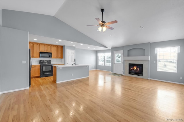 kitchen featuring black appliances, plenty of natural light, open floor plan, and a sink