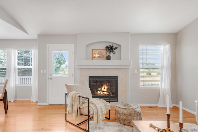 23612 E Mississippi Cir, Aurora, CO 80018 - living area featuring a tiled fireplace, light wood-type flooring, and healthy amount of natural light