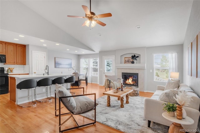 23612 E Mississippi Cir, Aurora, CO 80018 - living area featuring lofted ceiling, light wood-type flooring, a tiled fireplace, recessed lighting, and a ceiling fan