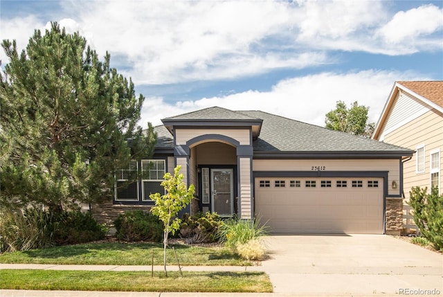 23612 E Mississippi Cir, Aurora, CO 80018 - view of front of home featuring a garage, driveway, roof with shingles, and stone siding