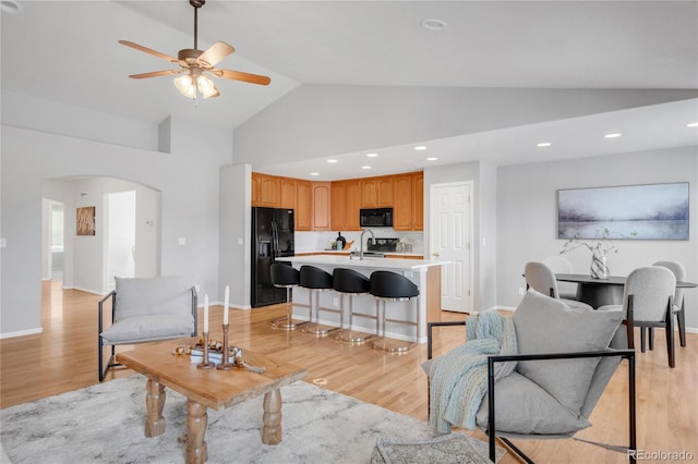 23612 E Mississippi Cir, Aurora, CO 80018 - living room featuring arched walkways, light wood-style flooring, a ceiling fan, recessed lighting, and high vaulted ceiling