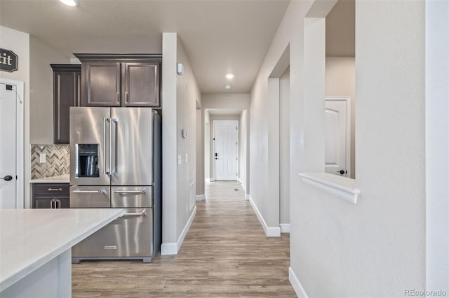 kitchen featuring high quality fridge, dark brown cabinetry, light wood-type flooring, and backsplash