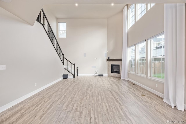 unfurnished living room featuring a high ceiling and light wood-type flooring