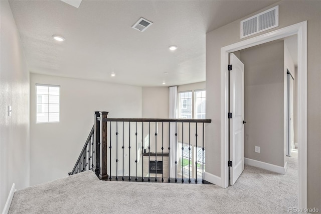 hallway featuring light colored carpet and a wealth of natural light