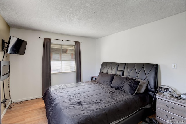 bedroom with a textured ceiling and light wood-type flooring