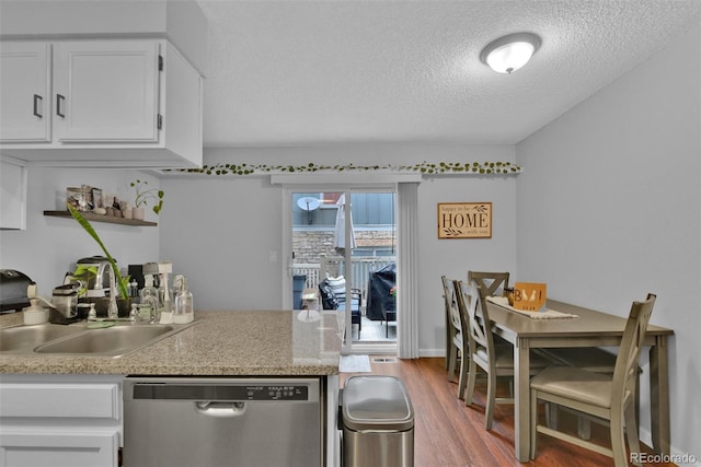 kitchen featuring wood-type flooring, sink, stainless steel dishwasher, white cabinets, and a textured ceiling