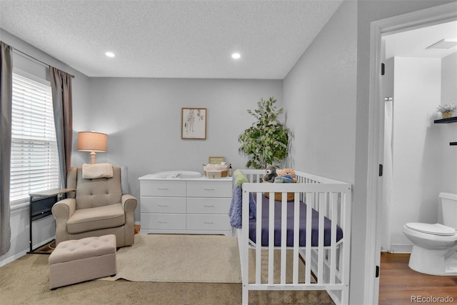 carpeted bedroom with a textured ceiling and a crib