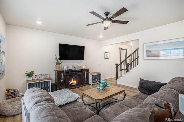 living area with wood finished floors, baseboards, ceiling fan, stairway, and recessed lighting