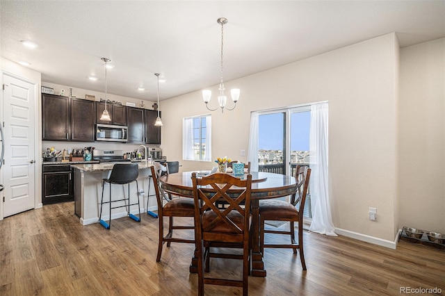 dining area with baseboards, recessed lighting, wood finished floors, and a notable chandelier